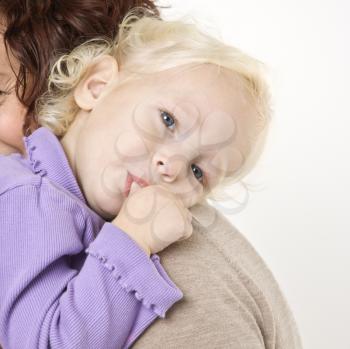 Royalty Free Photo of a Female Toddler Sucking Her Thumb While Her Mother Holds Her
