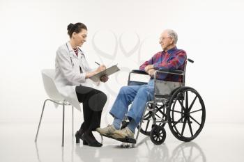 Royalty Free Photo of a Doctor Taking Notes With an Elderly Man in a Wheelchair