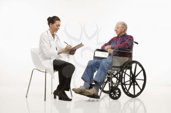 Royalty Free Photo of a Doctor Taking Notes With an Elderly Male in a Wheelchair