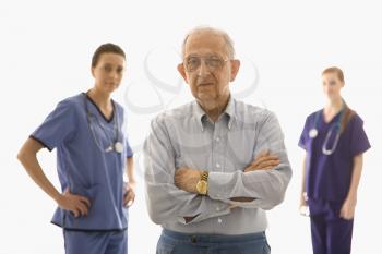 Royalty Free Photo of an Elderly Man in the Foreground With Two Female Medical Practitioners 