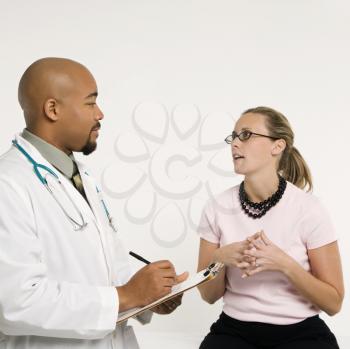 Royalty Free Photo of a Doctor With a Clipboard Talking to a Patient in a Doctor's Office