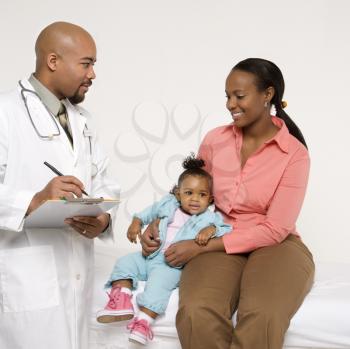 Royalty Free Photo of a Mother and Baby Girl Talking to Their Male Pediatrician