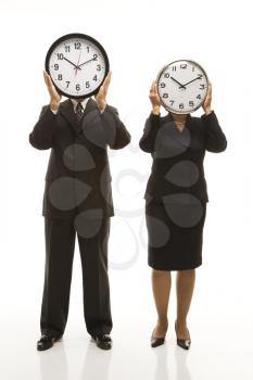 Royalty Free Photo of a Middle-aged Businessman and Businesswoman Holding Clocks in Front of Their Heads