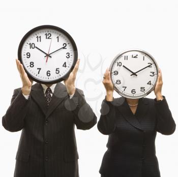 Royalty Free Photo of a Middle-aged Businessman and Businesswoman Holding Clocks in Front of Their Heads