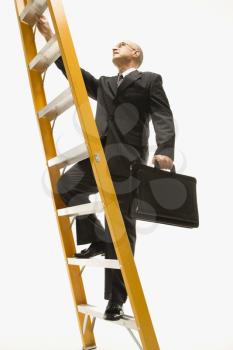 Royalty Free Photo of a Middle-aged Businessman Climbing a Ladder and Carrying a Briefcase