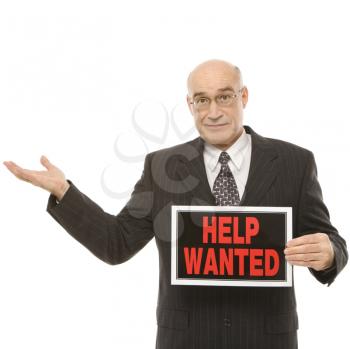 Royalty Free Photo of a Middle-aged Businessman Holding Up a Help Wanted Sign