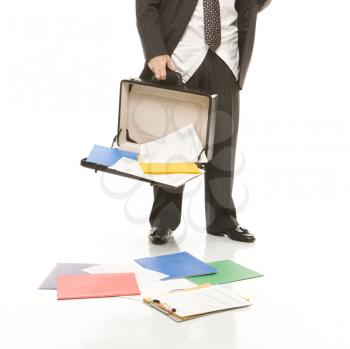 Royalty Free Photo of a Businessman Holding Open a Briefcase With Papers Falling Out