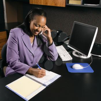 Royalty Free Photo of a Businesswoman Talking on a Cellphone and Writing in a Planner