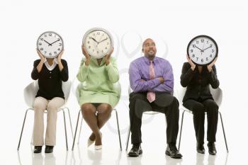 Royalty Free Photo of Businesswomen Sitting Holding Clocks Over Their Faces While Businessman Watches