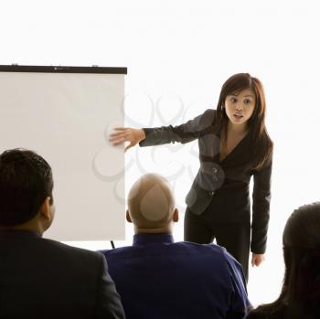 Royalty Free Photo of a Woman Standing in Front of a Business Group Pointing to a Presentation