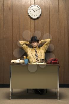 Royalty Free Photo of a Retro Businessman Sitting at a Desk Wearing a Fedora