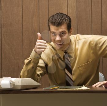 Royalty Free Photo of a Retro Businessman Sitting at a Desk Giving an Overenthusiastic Thumbs Up