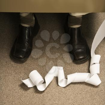 Royalty Free Photo of a Long Adding Machine Printout Curled Up at the Feet of a Businessman