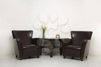 Royalty Free Photo of Two Brown Armchairs and a Table With Daffodils 