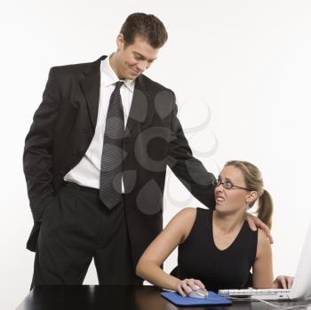 Royalty Free Photo of a Man Sexually Harassing a Woman Sitting at a Computer
