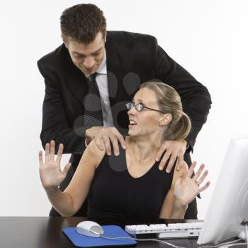 Royalty Free Photo of a Man Sexually Harassing a Woman Sitting at a Computer