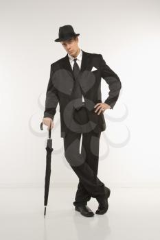 Royalty Free Photo of a Businessman Wearing a Fedora Leaning on an Umbrella