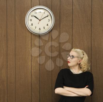 Royalty Free Photo of a Female in a Vintage Outfit Looking Up at a Clock