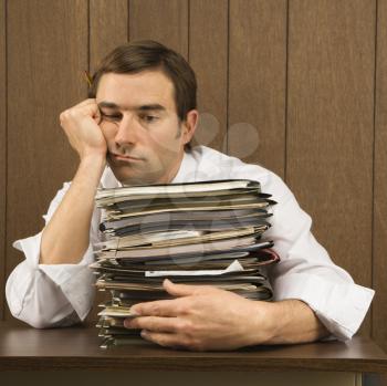 Royalty Free Photo of a Man With Overwhelmed Face Holding Lots of Paperwork