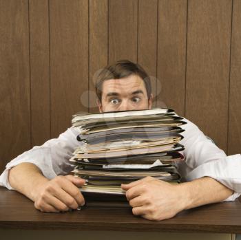 Royalty Free Photo of a Man Peeking Over a Stack of Paperwork