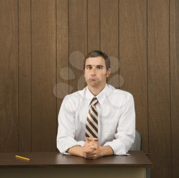Royalty Free Photo of a Male Sitting at a Desk With a Pencil Beside Him