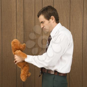Royalty Free Photo of a Man Holding a Stuffed Animal and Looking Upset