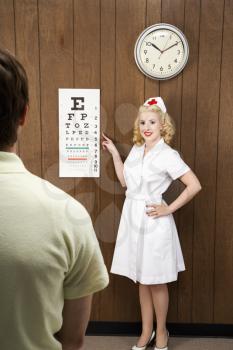 Royalty Free Photo of a Female Nurse Pointing Out an Eye Chart to a Male Patient