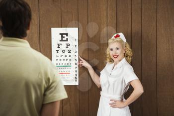 Royalty Free Photo of a Female Nurse Pointing Out an Eye Chart to a Male Patient