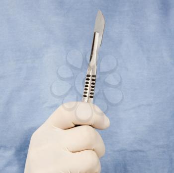 Royalty Free Photo of a Male Surgeon's Gloved Hand Holding a Scalpel