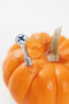 Royalty Free Photo of a Silver Phillips Head Screw Drilled into a Side of a Pumpkin