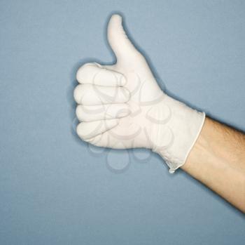 Hand wearing white rubber glove giving the thumbs up signal.