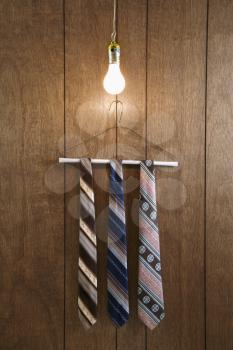 Royalty Free Photo of Three Retro Ties Hanging on a Hanger With a Light Bulb