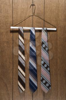 Royalty Free Photo of Three Retro Ties Hanging on a Wire Hanger Against Wood Paneling