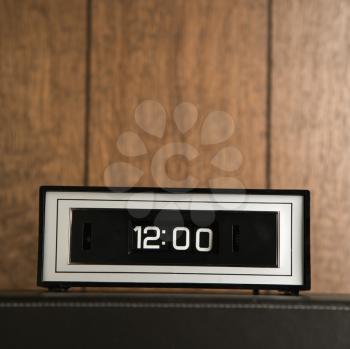 Royalty Free Photo of a Retro Alarm Clock Set for 12:00 Against Wood Paneling