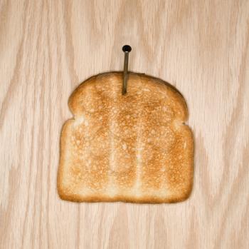 Royalty Free Photo of a Slice of Toast Nailed to Wood