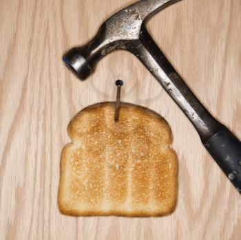 Royalty Free Photo of a Slice of Toast Nailed to Wood With a Hammer