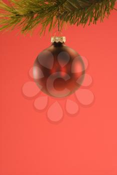 Royalty Free Photo of a Round Red Christmas Ornament Hanging From a Pine Branch
