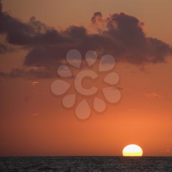 Royalty Free Photo of the Sun Setting Over the Horizon of Ocean