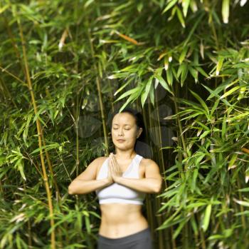 Royalty Free Photo of a Woman in Fitness Attire Standing in a Yoga Position with Eyes Closed in Bamboo Forest in Maui, Hawaii