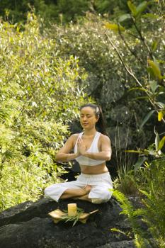 Royalty Free Photo of a Woman Sitting on a Boulder in the Forest Meditating With Candle in Maui, Hawaii