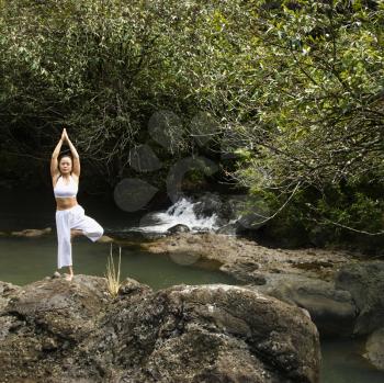 Royalty Free Photo of a Woman Doing Yoga Balancing on a Boulder by a Creek in Maui, Hawaii
