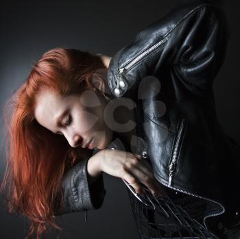 Royalty Free Photo of a Woman Wearing a Leather Jacket Leaning Over a Chair
