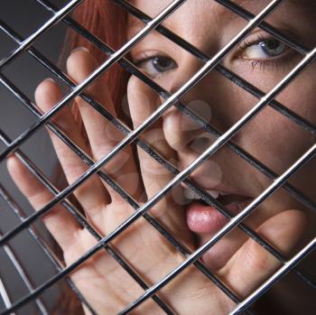 Royalty Free Photo of a Pretty Redhead Woman With Her Face Behind a Metal Pattern