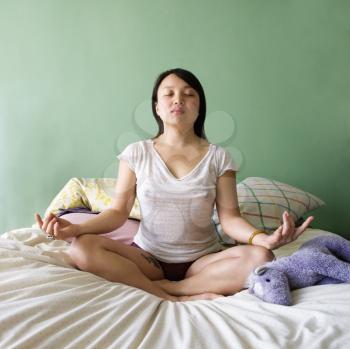 Royalty Free Photo of a Woman Sitting on a Bed Meditating