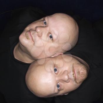 Royalty Free Photo of an Aeriel View of Identical Twin Men Sitting Back to Back and Looking Up