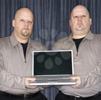 Royalty Free Photo of Identical Twins Holding a Laptop