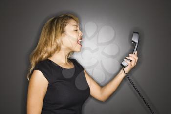 Royalty Free Photo of a Woman Yelling Into a Telephone Receiver