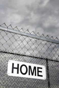 Royalty Free Photo of a Home Sign Hanging on a Metal Chain Link Fence