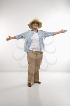 Royalty Free Photo of a Middle-aged Woman Wearing a Straw Hat Holding Arms Outstretched