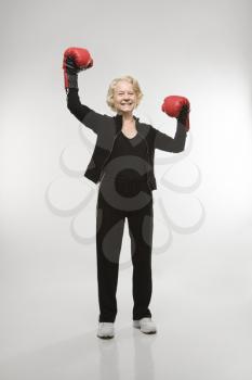 Royalty Free Photo of an Older Woman Wearing Boxing Gloves Raised in the Air